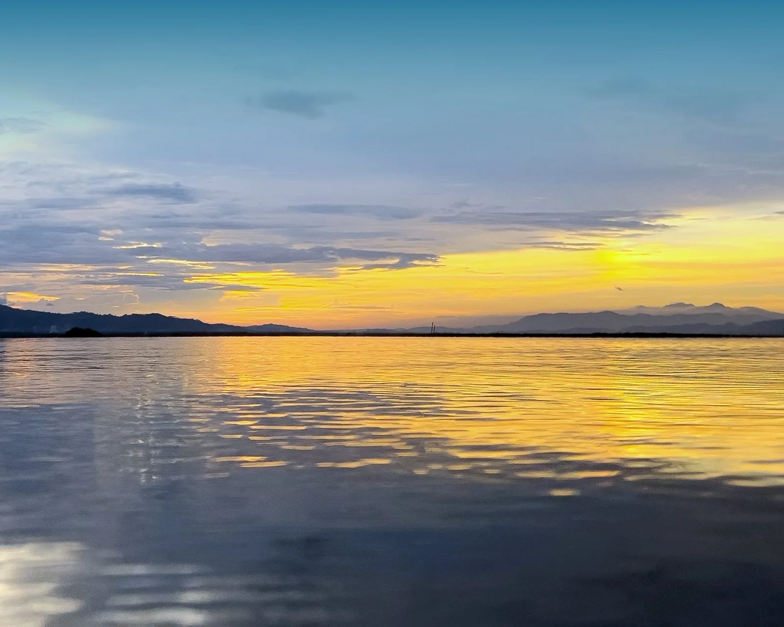 A gold sunrise horizon over calm water